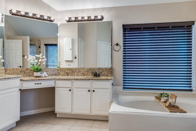 bathroom with double vanity, a garden tub, tile patterned flooring, and a sink