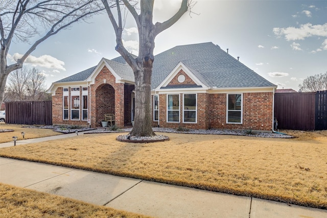 view of front of house featuring fence, a front lawn, and brick siding