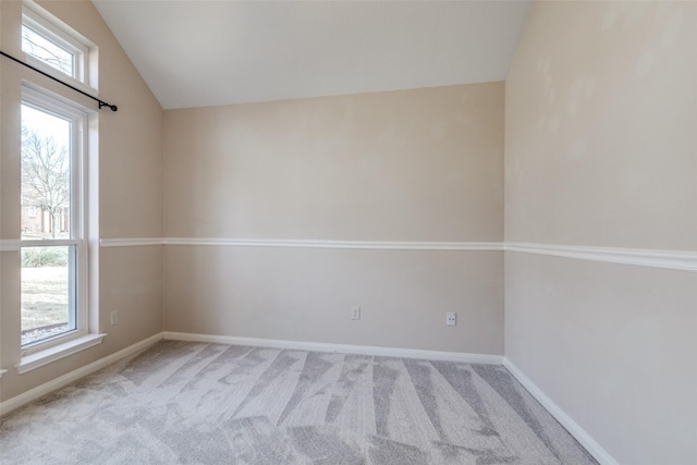 carpeted spare room featuring lofted ceiling and baseboards