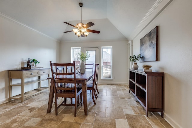 dining space featuring lofted ceiling, stone tile floors, baseboards, and crown molding