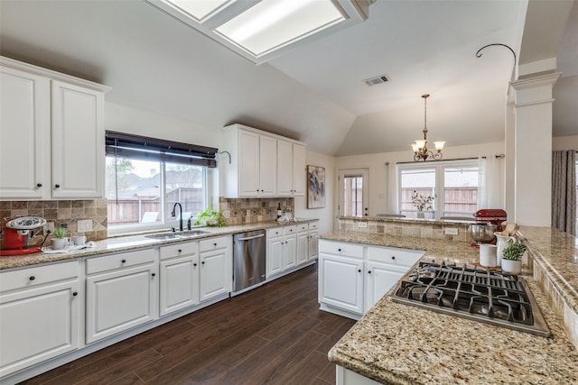 kitchen featuring visible vents, dark wood-style floors, vaulted ceiling, stainless steel appliances, and a sink