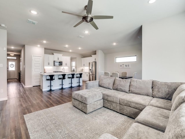 living area featuring recessed lighting, dark wood-style flooring, and visible vents