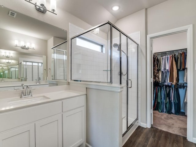 bathroom featuring visible vents, a shower stall, vanity, and wood finished floors