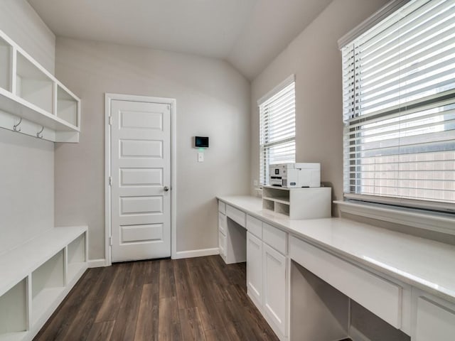 interior space featuring lofted ceiling, built in desk, dark wood finished floors, and baseboards