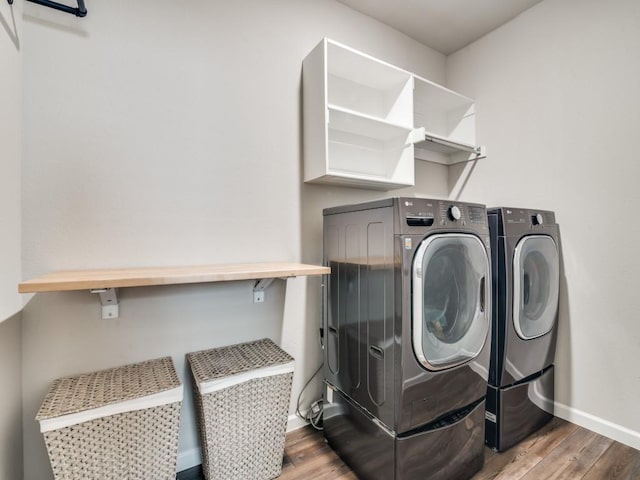 washroom featuring laundry area, baseboards, wood finished floors, and independent washer and dryer