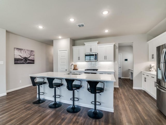 kitchen featuring dark wood-type flooring, a sink, visible vents, appliances with stainless steel finishes, and tasteful backsplash