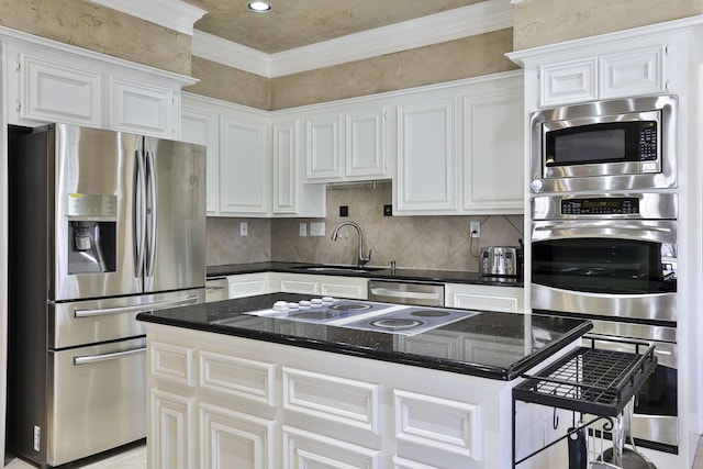 kitchen featuring stainless steel appliances, backsplash, white cabinets, a sink, and a kitchen island