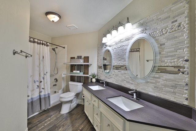 bathroom with toilet, decorative backsplash, a sink, and wood finished floors