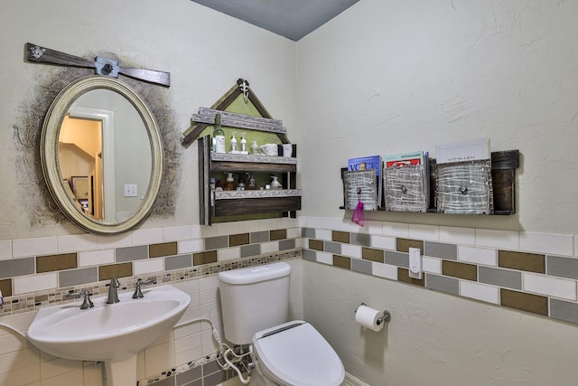 bathroom featuring a wainscoted wall, a sink, and toilet