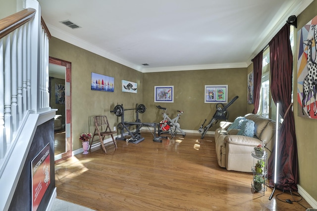 exercise room featuring baseboards, crown molding, visible vents, and wood finished floors