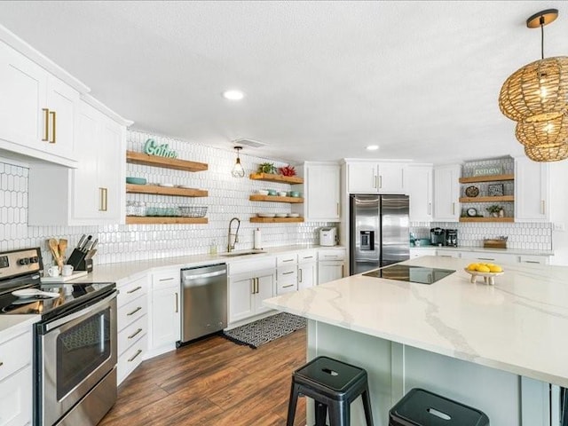 kitchen featuring a breakfast bar, a sink, white cabinetry, appliances with stainless steel finishes, and open shelves