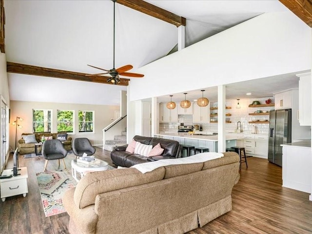 living room with ceiling fan, stairway, dark wood-style flooring, high vaulted ceiling, and beam ceiling