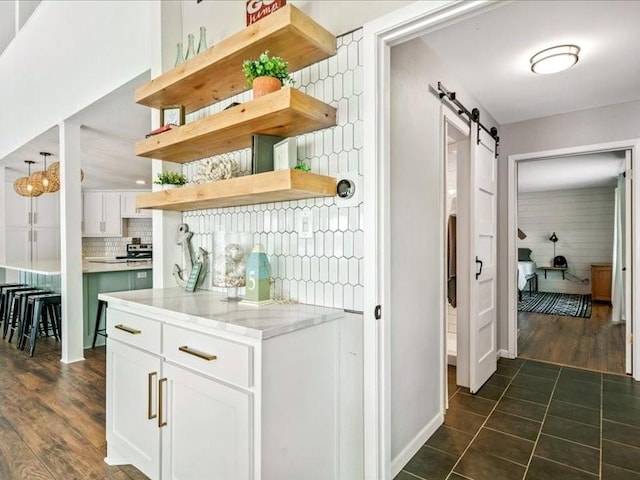 bar featuring dark wood-style flooring, backsplash, and a barn door