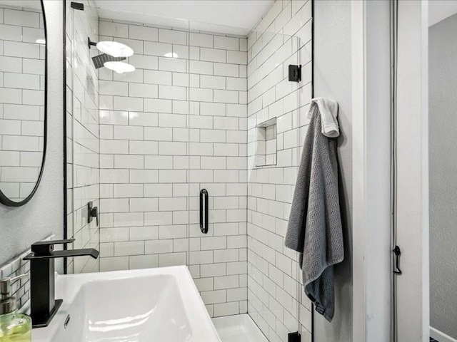 bathroom with a stall shower and a sink