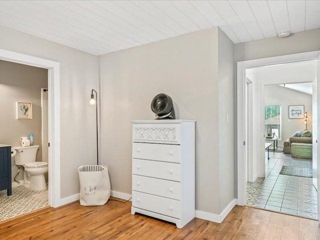 corridor featuring light wood-type flooring, wood ceiling, and baseboards