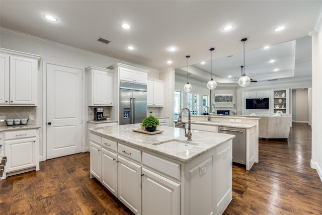 kitchen with appliances with stainless steel finishes, open floor plan, a kitchen island with sink, a fireplace, and a sink