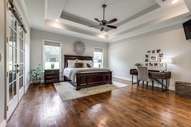 bedroom featuring baseboards, a tray ceiling, hardwood / wood-style floors, and ornamental molding