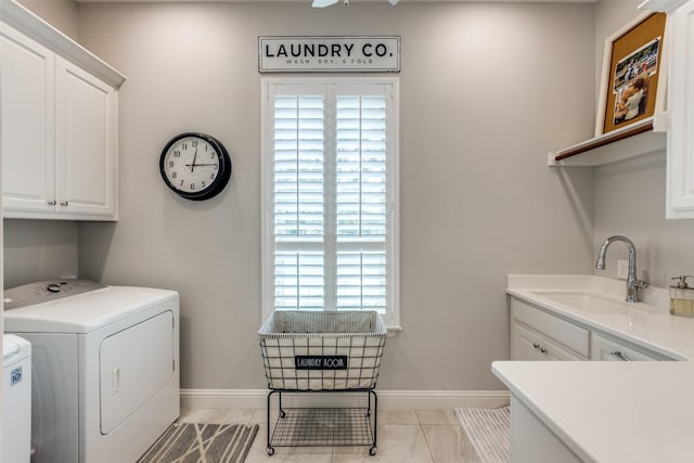 laundry area with cabinet space, baseboards, washer and clothes dryer, a sink, and light tile patterned flooring