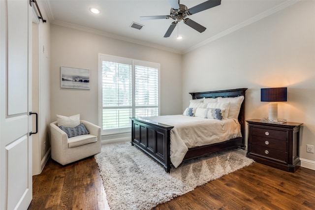 bedroom with dark wood-style flooring, visible vents, a barn door, ornamental molding, and baseboards