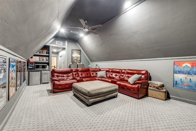 carpeted home theater room with a textured ceiling, vaulted ceiling, visible vents, and baseboards