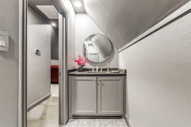 bathroom featuring a textured wall, vanity, and baseboards