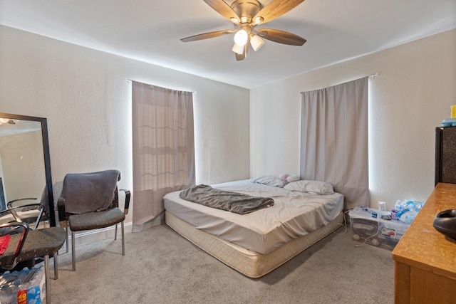 carpeted bedroom with ceiling fan and a textured wall