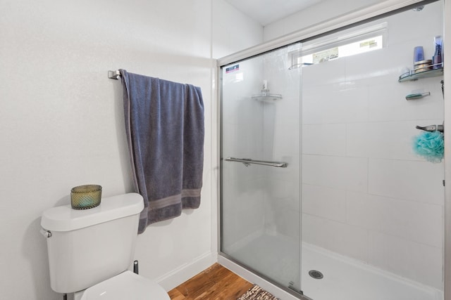 full bath with baseboards, a shower stall, toilet, and wood finished floors