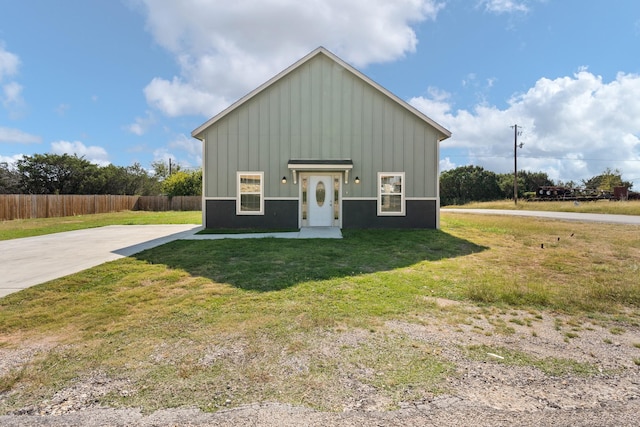 view of front facade with board and batten siding, a front yard, and fence