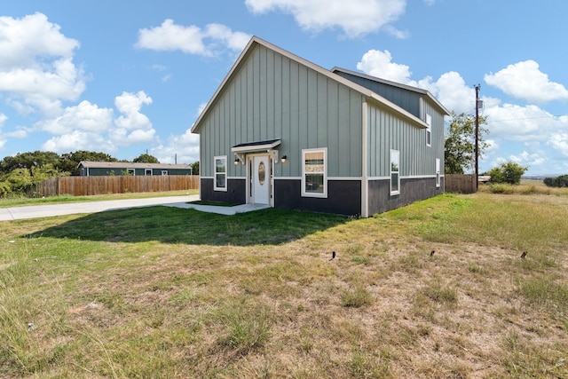 exterior space with fence, board and batten siding, and a yard