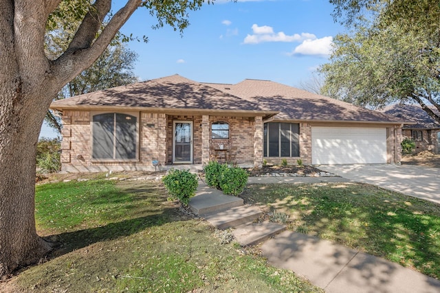 single story home with driveway, roof with shingles, a front yard, a garage, and brick siding