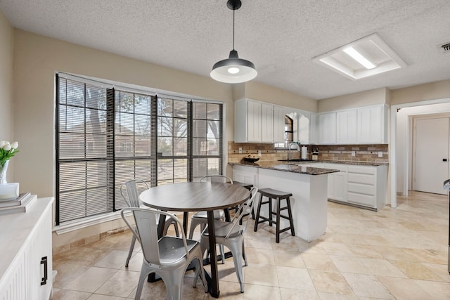 kitchen featuring tasteful backsplash, a peninsula, white cabinetry, and a sink