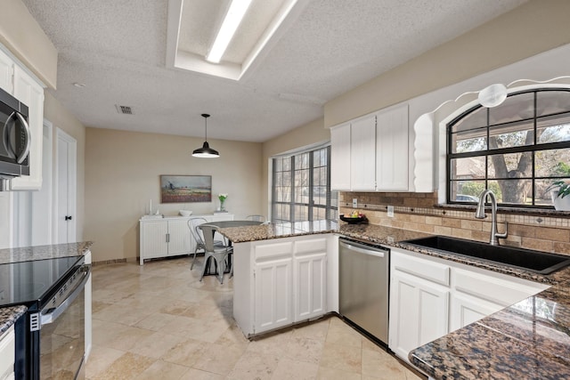 kitchen with a sink, backsplash, stainless steel dishwasher, a peninsula, and white cabinets