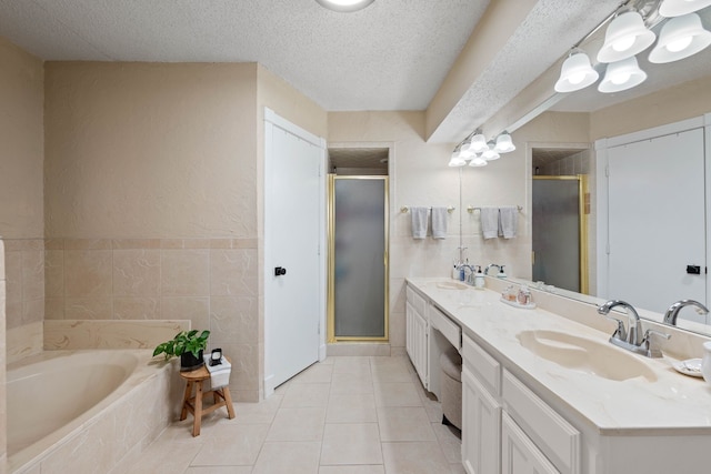 full bathroom featuring a textured ceiling, a garden tub, a stall shower, and a sink