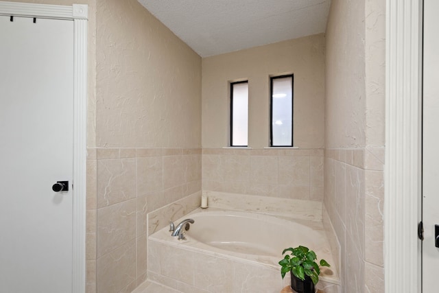 full bathroom featuring a textured ceiling, a garden tub, and a textured wall