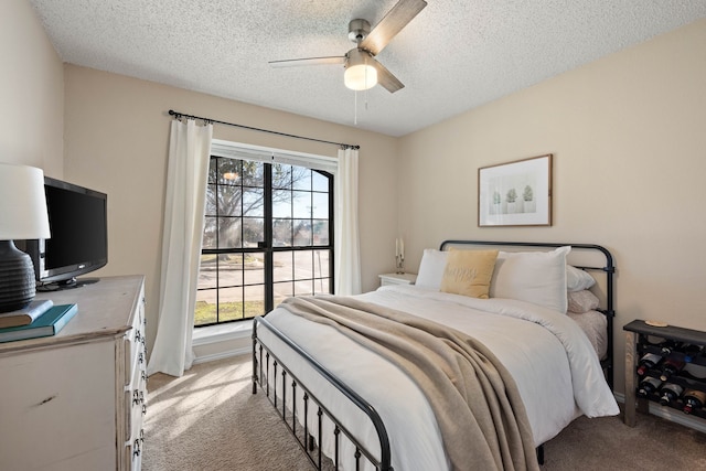 bedroom with baseboards, light carpet, a textured ceiling, and a ceiling fan