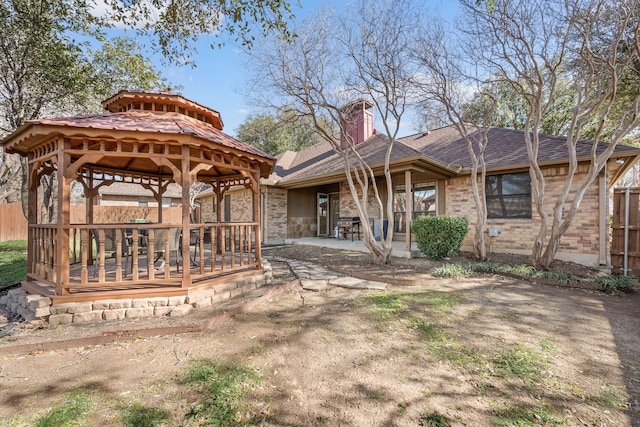 exterior space featuring a shingled roof, fence, a gazebo, a chimney, and a patio area