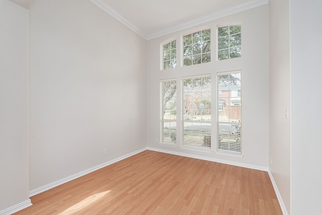 spare room with ornamental molding, light wood-style flooring, and baseboards