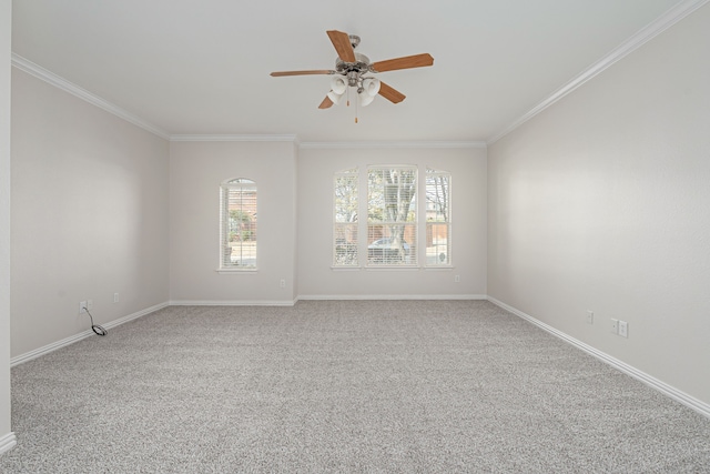 carpeted empty room with a ceiling fan, baseboards, and crown molding