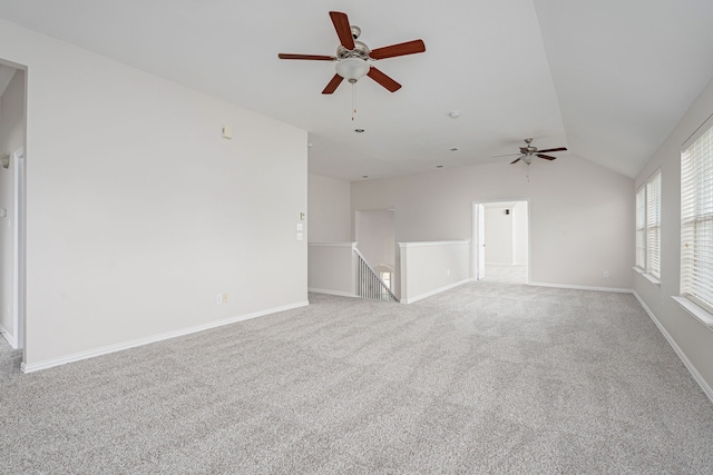 carpeted empty room featuring baseboards and vaulted ceiling