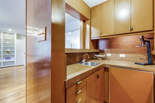 kitchen with light countertops, a sink, light wood-style flooring, and decorative backsplash