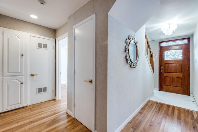 foyer with light wood finished floors, baseboards, visible vents, and a chandelier