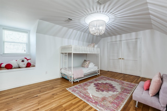 bedroom with baseboards, a closet, visible vents, and wood finished floors