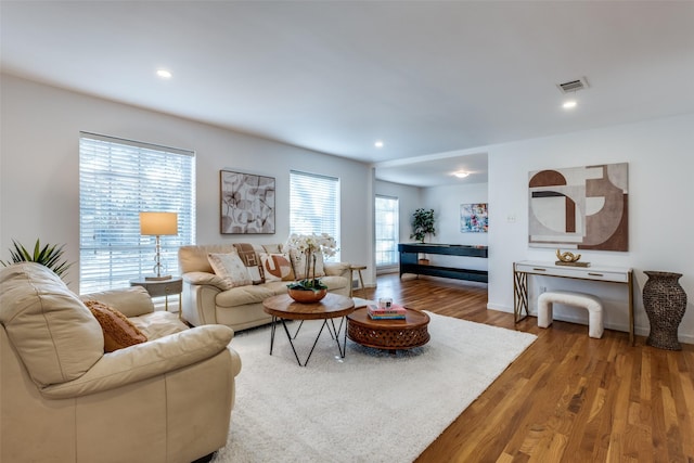 living area with recessed lighting, visible vents, baseboards, and wood finished floors