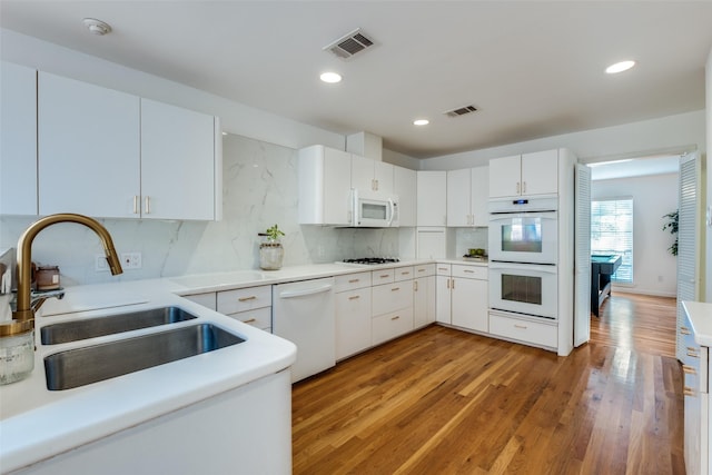 kitchen featuring white appliances, visible vents, a sink, and light wood finished floors