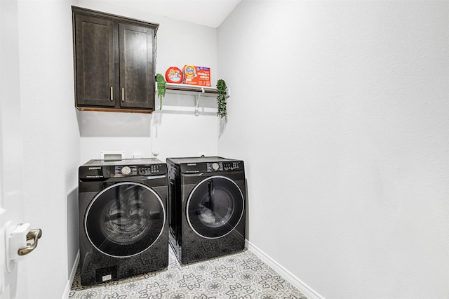 clothes washing area with washing machine and clothes dryer, cabinet space, and baseboards