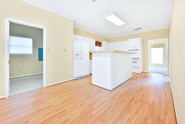 kitchen with white appliances, white cabinets, and crown molding