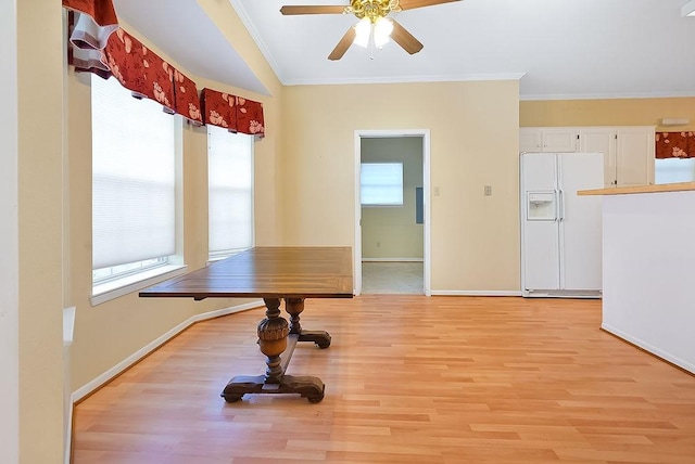 dining room featuring baseboards, ornamental molding, light wood-type flooring, and a healthy amount of sunlight