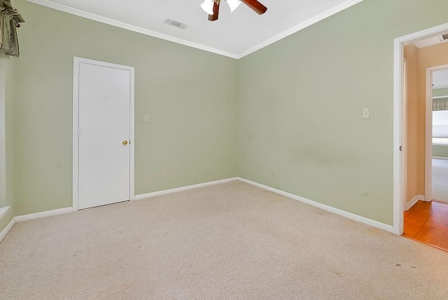 carpeted spare room featuring ceiling fan, ornamental molding, visible vents, and baseboards