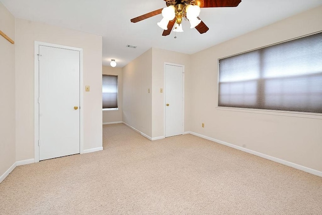 spare room with visible vents, baseboards, a ceiling fan, and light colored carpet