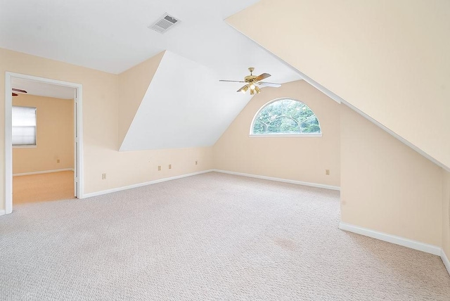 additional living space featuring visible vents, a ceiling fan, vaulted ceiling, baseboards, and carpet